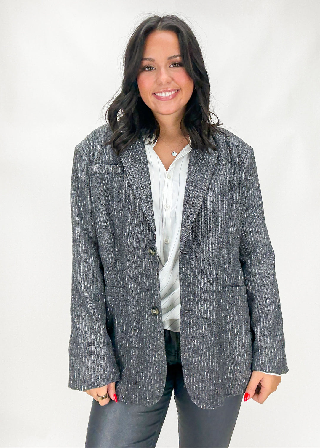 Woman wearing a gray blazer over a white shirt on a white background