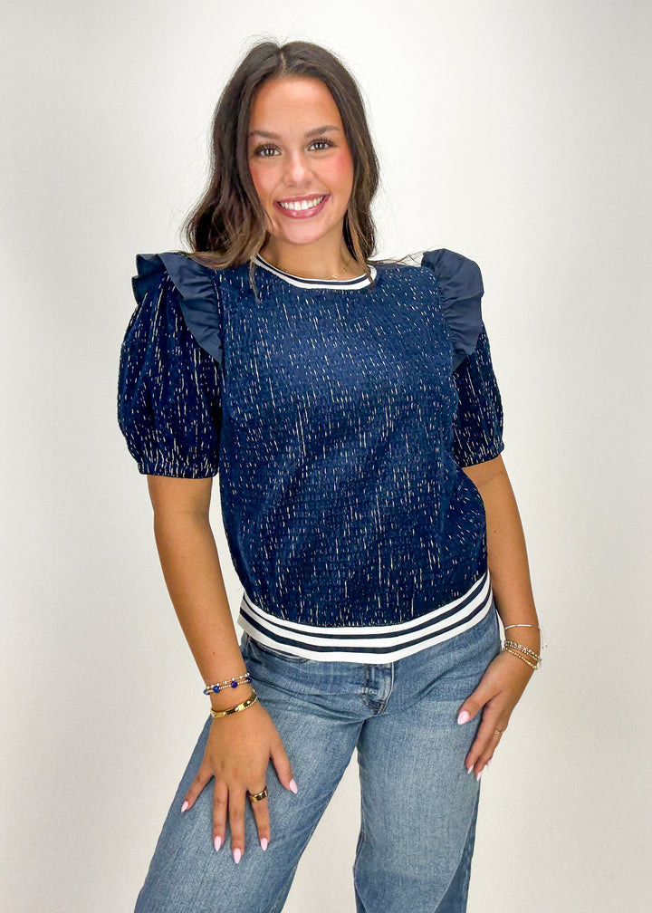 Woman wearing a blue top with ruffled sleeves and jeans 