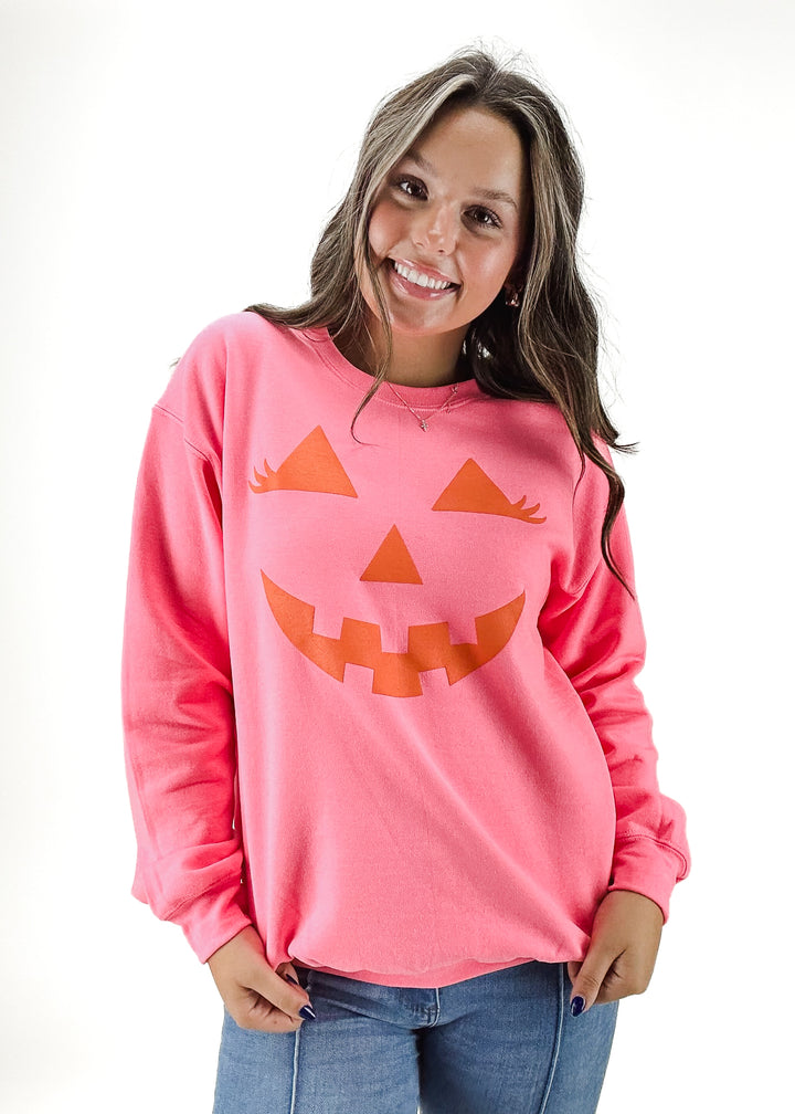 pink oversized crew neck sweatshirt with orange jack o lantern graphic on chest