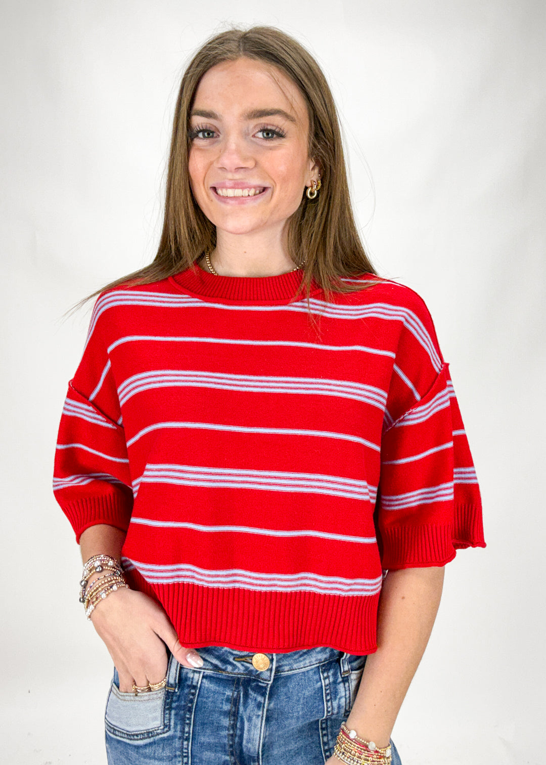 Woman wearing a red and blue striped sweater against a plain background