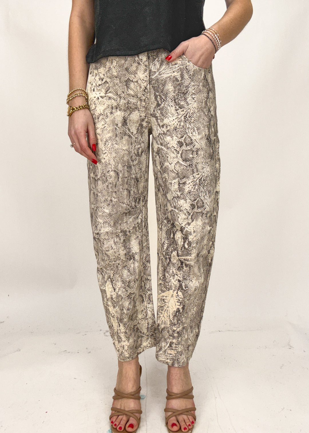 Person wearing snake print pants on a plain background