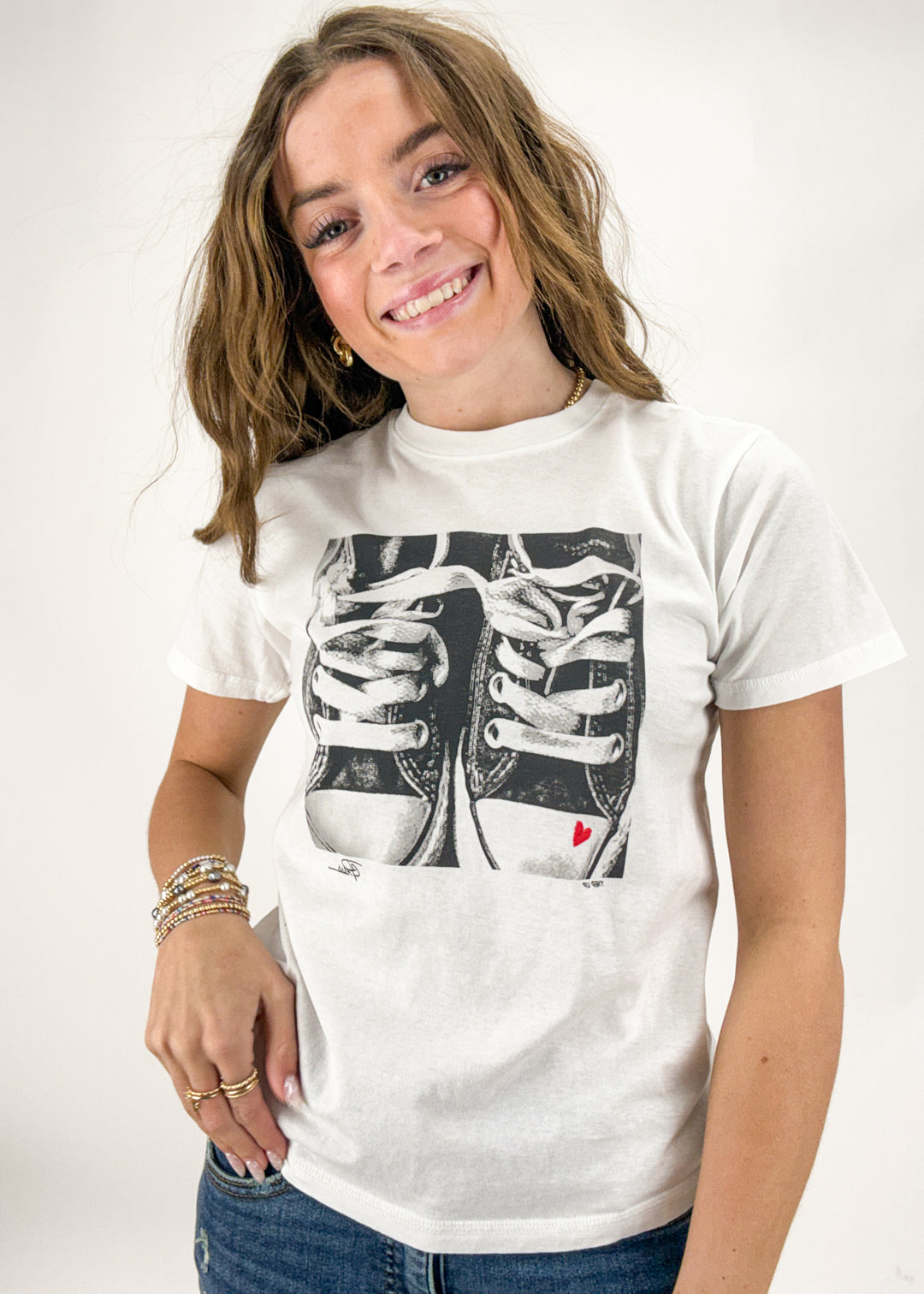 Person wearing a white t-shirt with a graphic design on a plain background