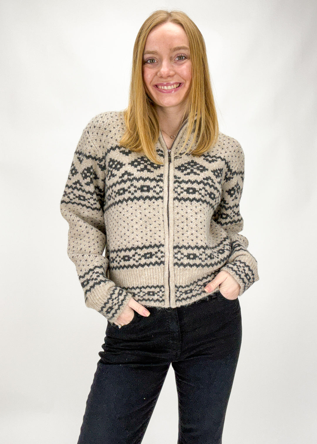 Woman wearing a patterned zip-up sweater against a white background