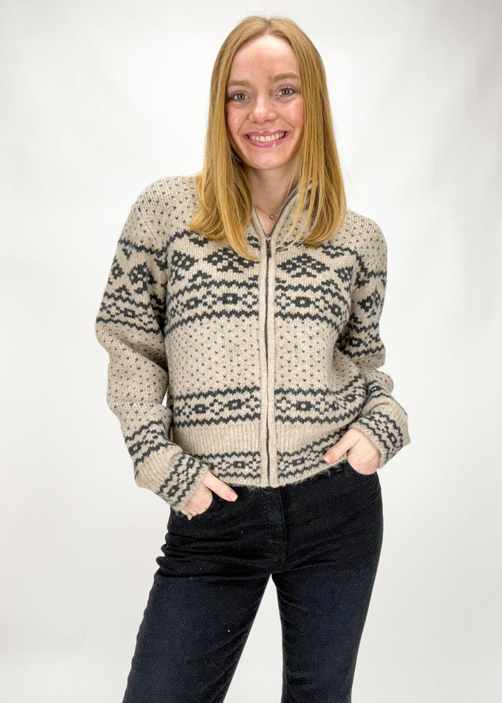 Woman wearing a patterned zip-up sweater against a white background