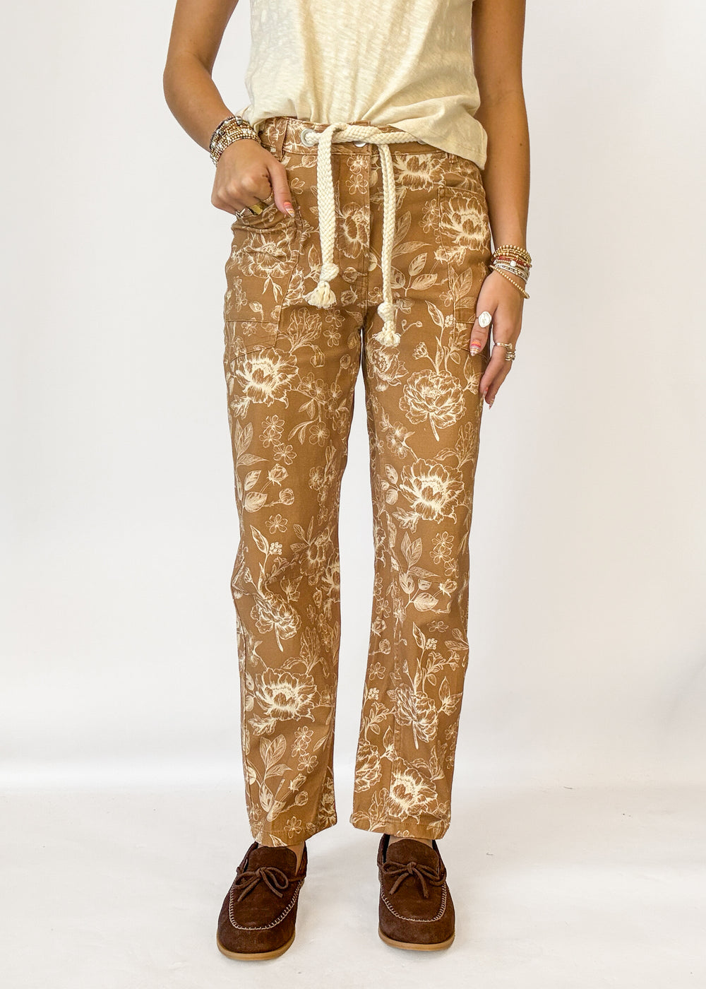 A person wearing tan pants with a cream floral print and a cream drawstring waist