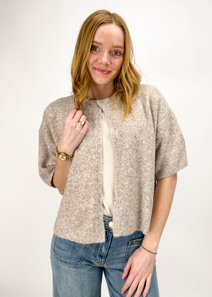 Woman wearing a tan short sleeve cardigan.