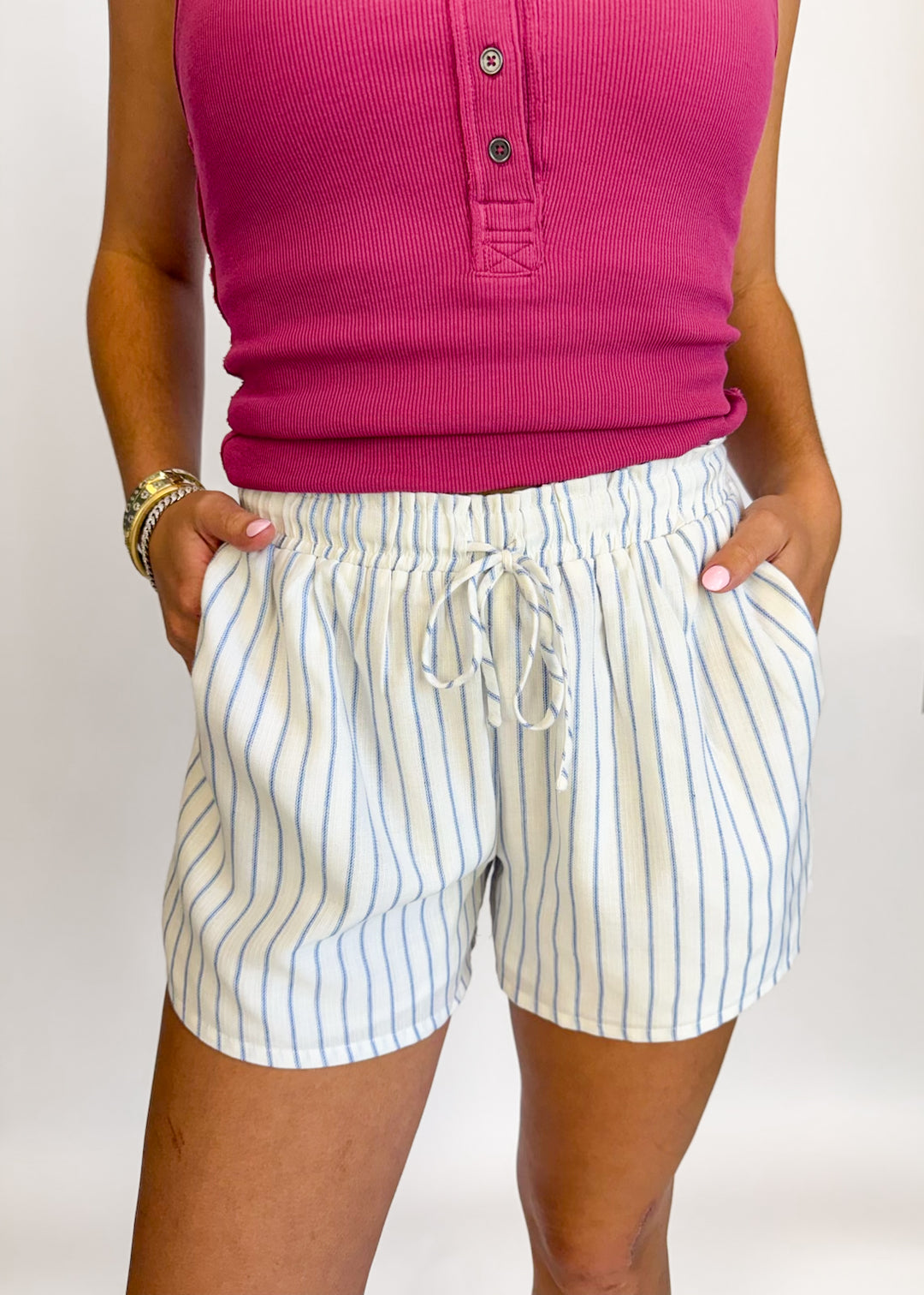 Person wearing a pink shirt and striped shorts on a white background