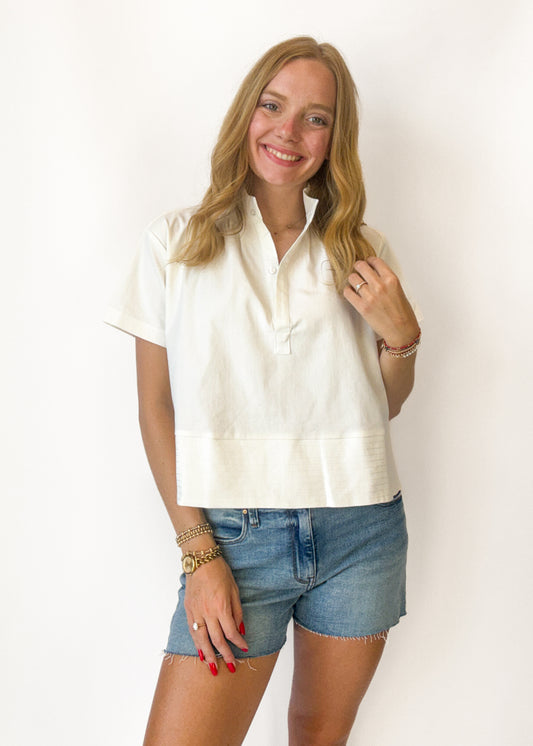 Woman wearing a white blouse and denim shorts against a white background