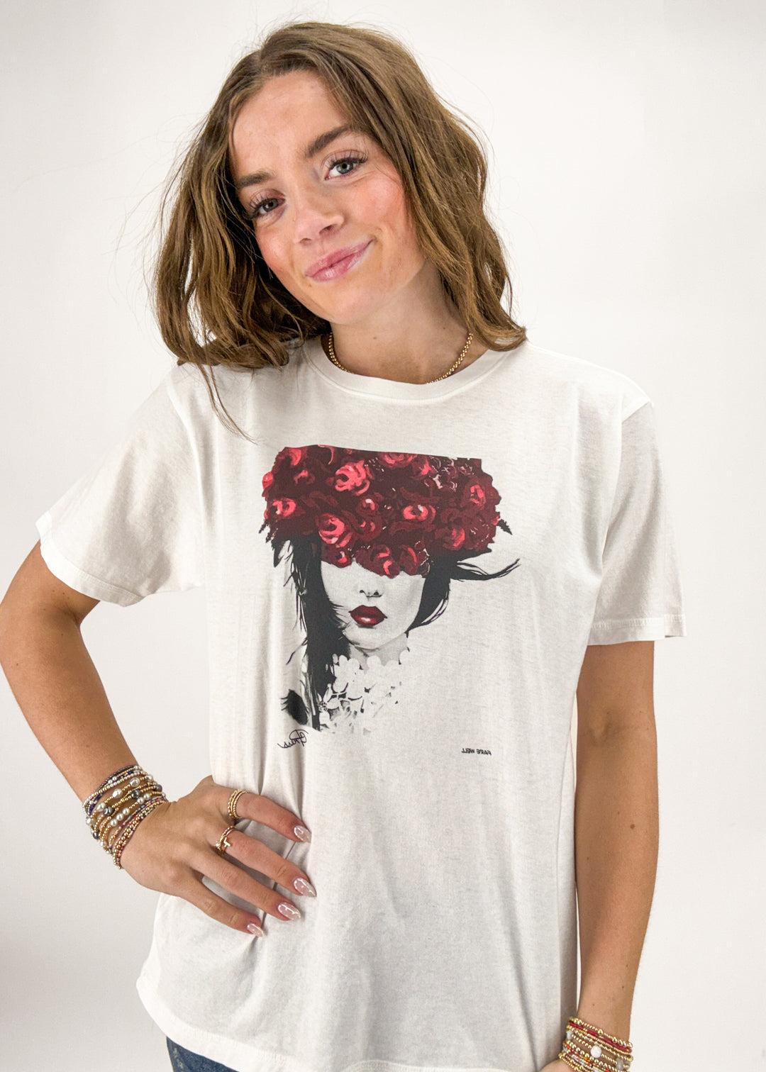 Person wearing a white t-shirt with a graphic design of a woman with red flowers on her head.