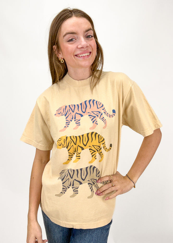 Woman wearing a beige t-shirt with tiger illustrations on a white background