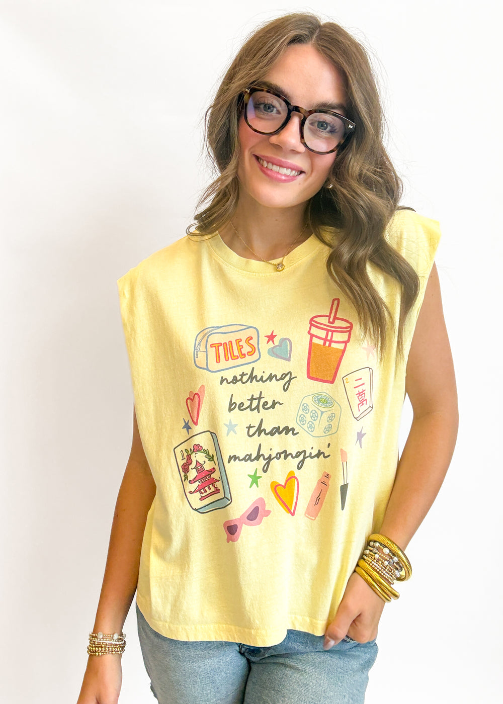 Woman wearing a yellow sleeveless shirt with graphics and text on a plain background