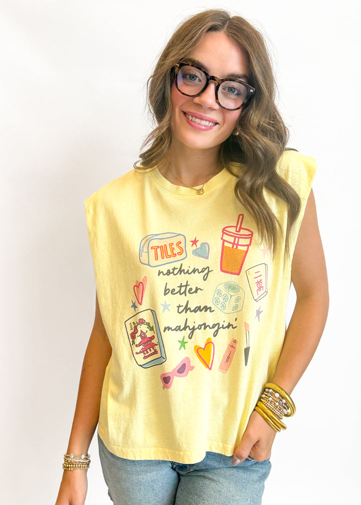 Woman wearing a yellow sleeveless shirt with graphics and text on a plain background