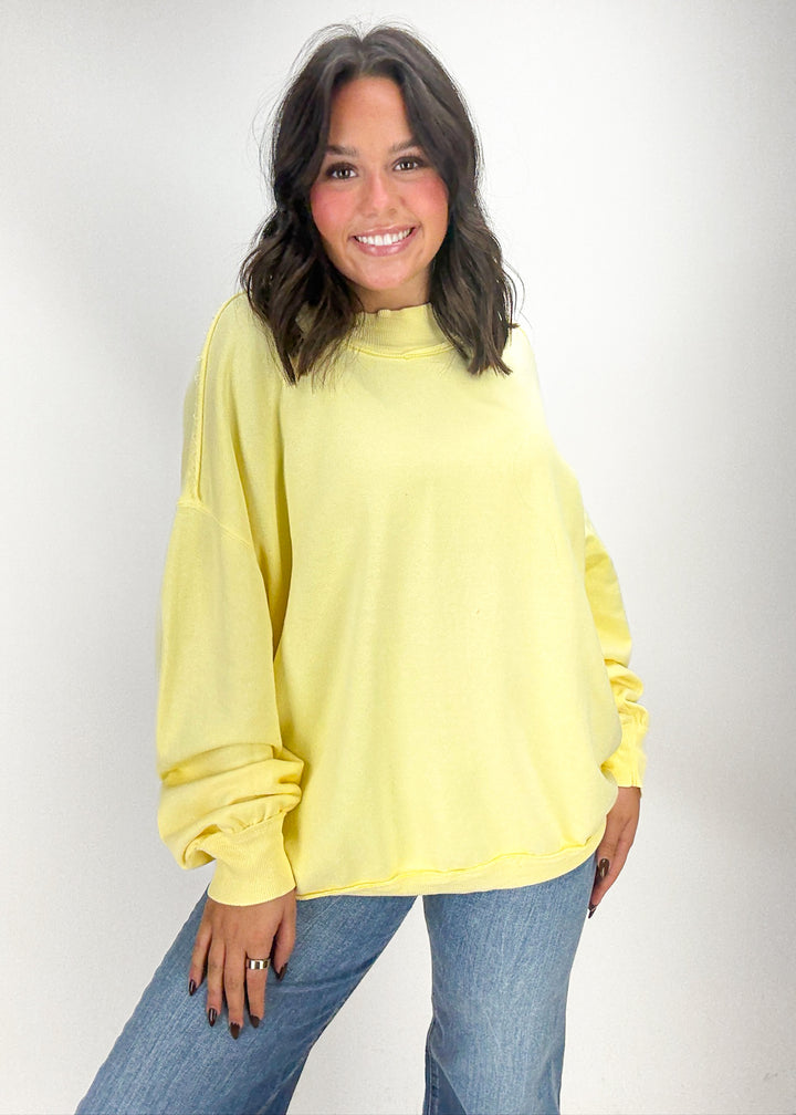 Woman wearing a yellow sweatshirt and blue jeans 